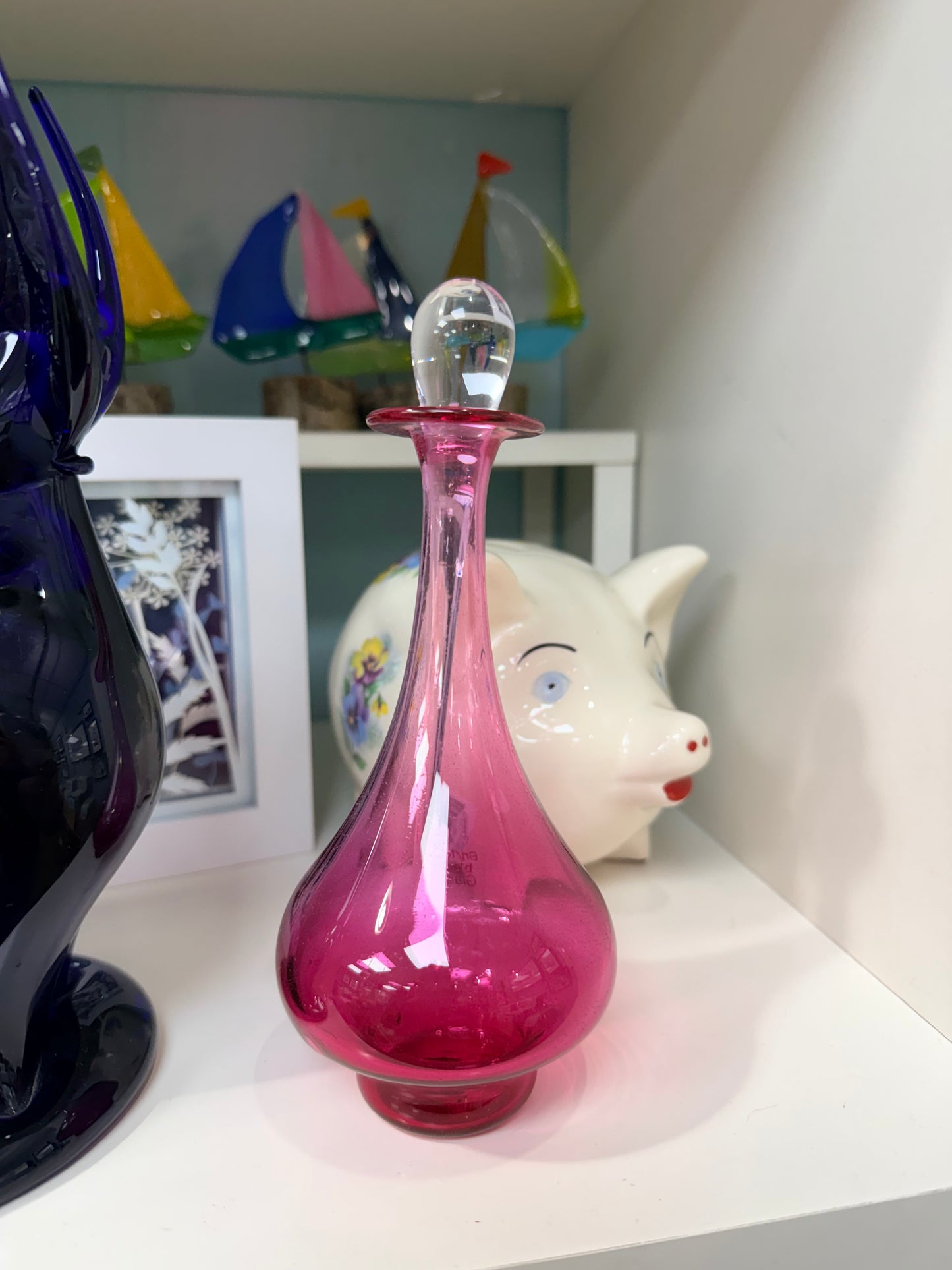 Pink glass vase on a shelf with decorative items