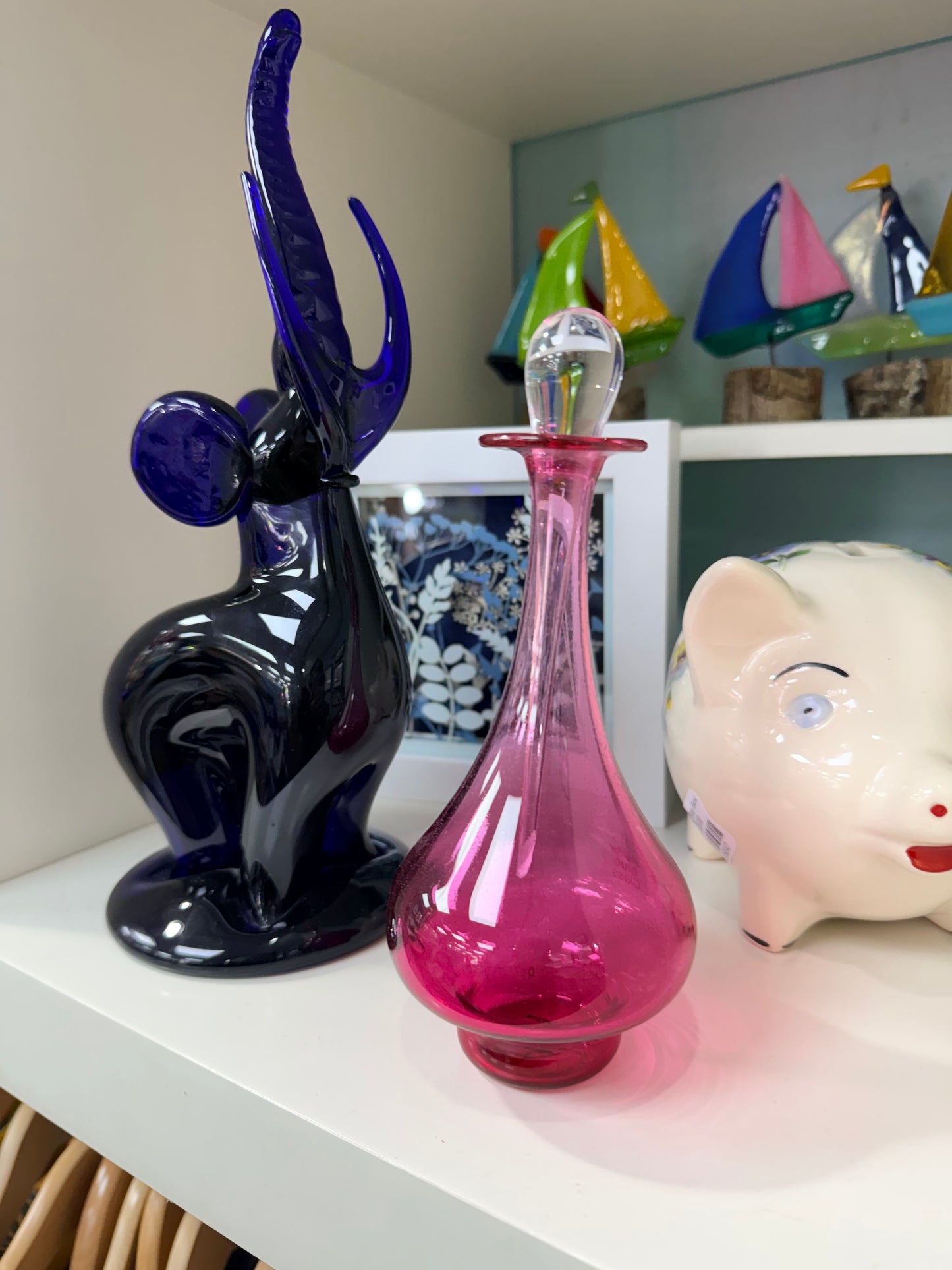Colorful glass sculptures on a shelf with decorative items in the background