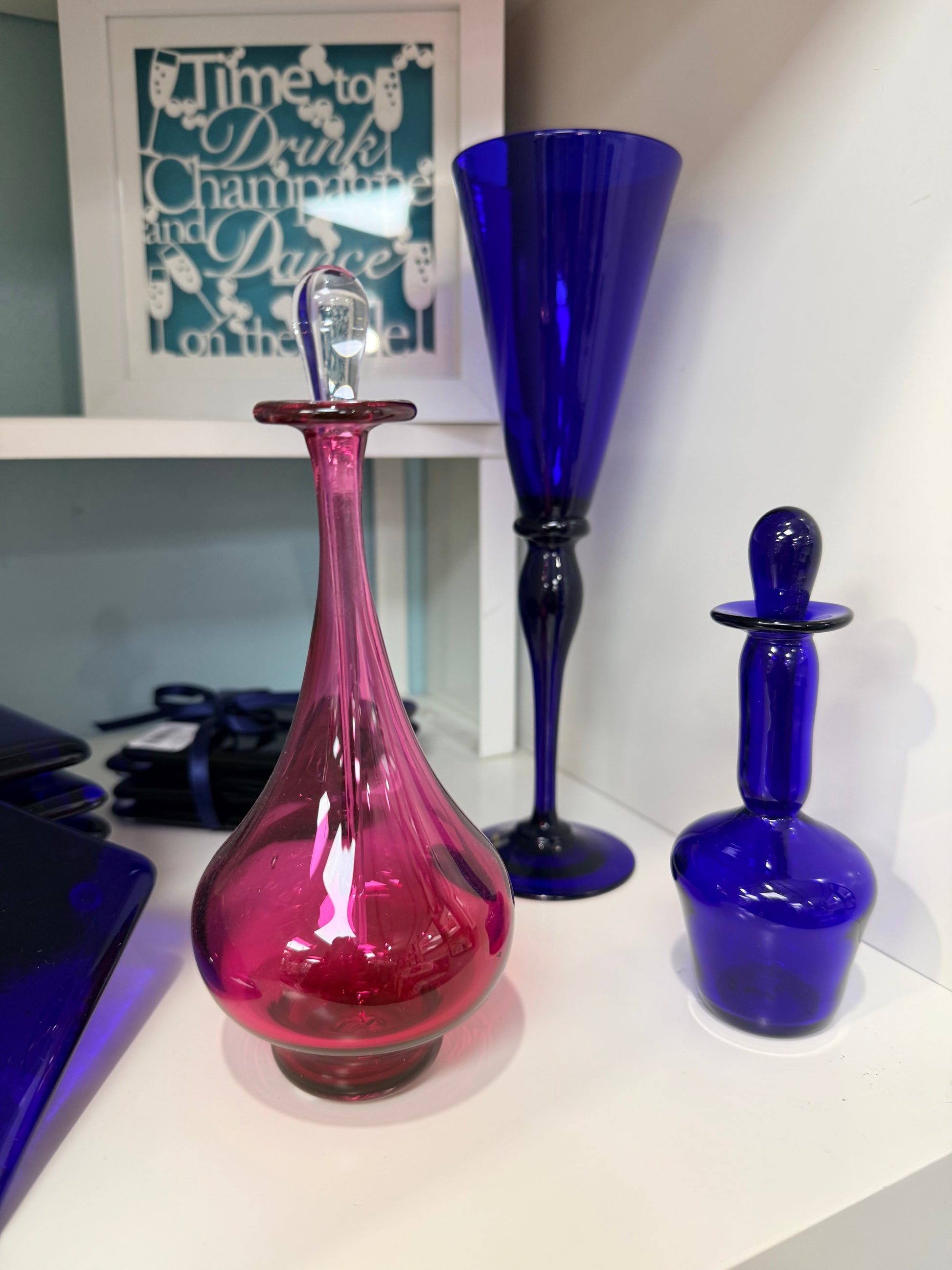 Two colorful glass vases, one blue and one pink, on a white surface.