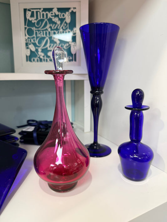 Two colorful glass vases, one blue and one pink, on a white surface.