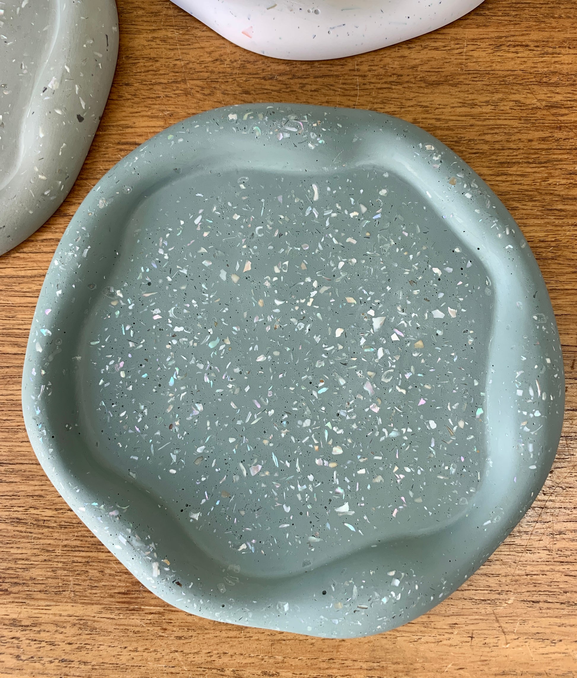 A flat wavy dish made from jesomite.  Green with white pearly flecks.