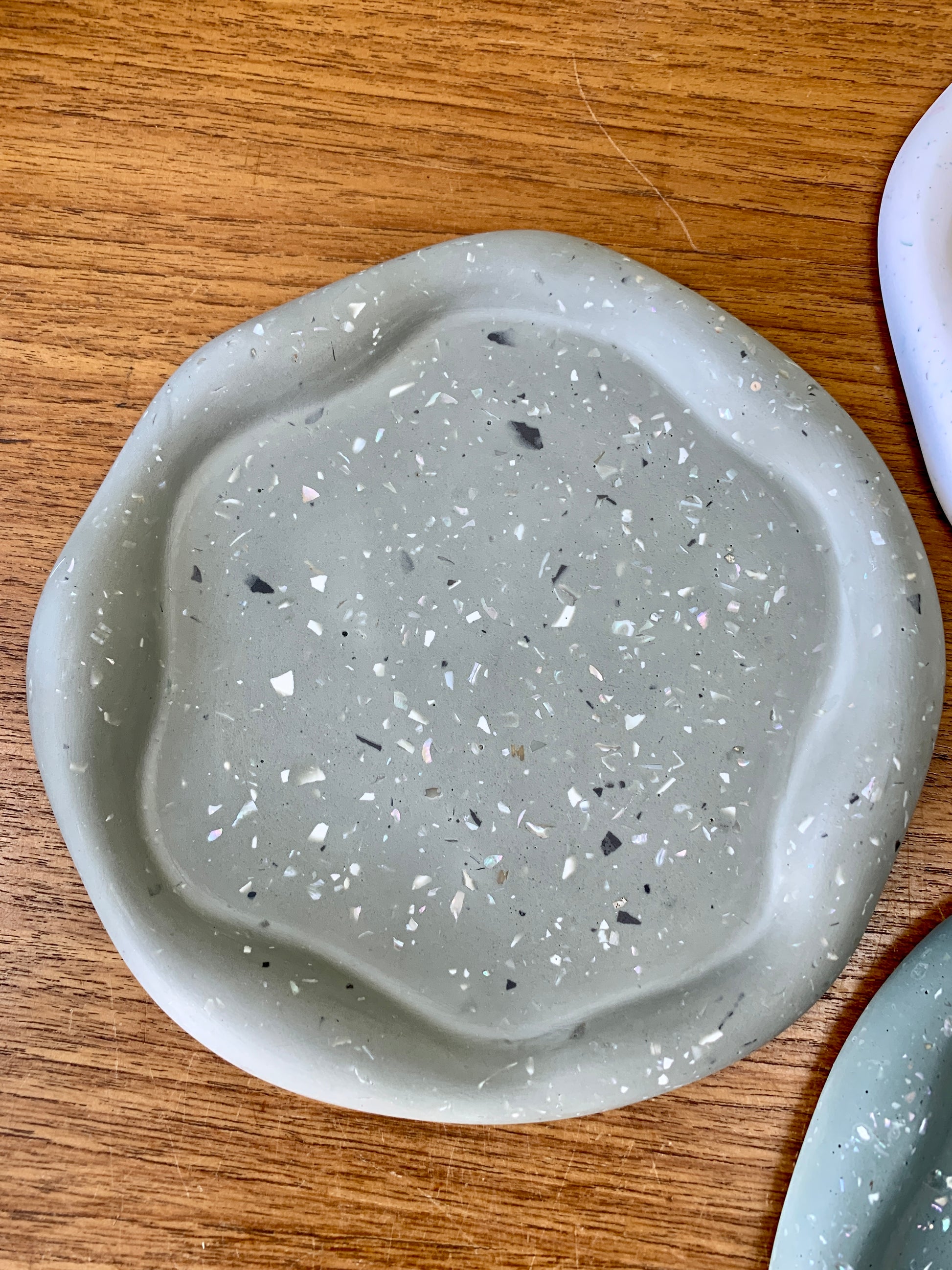 A wavy flat dish made from jesomite green with black and white flecks.
