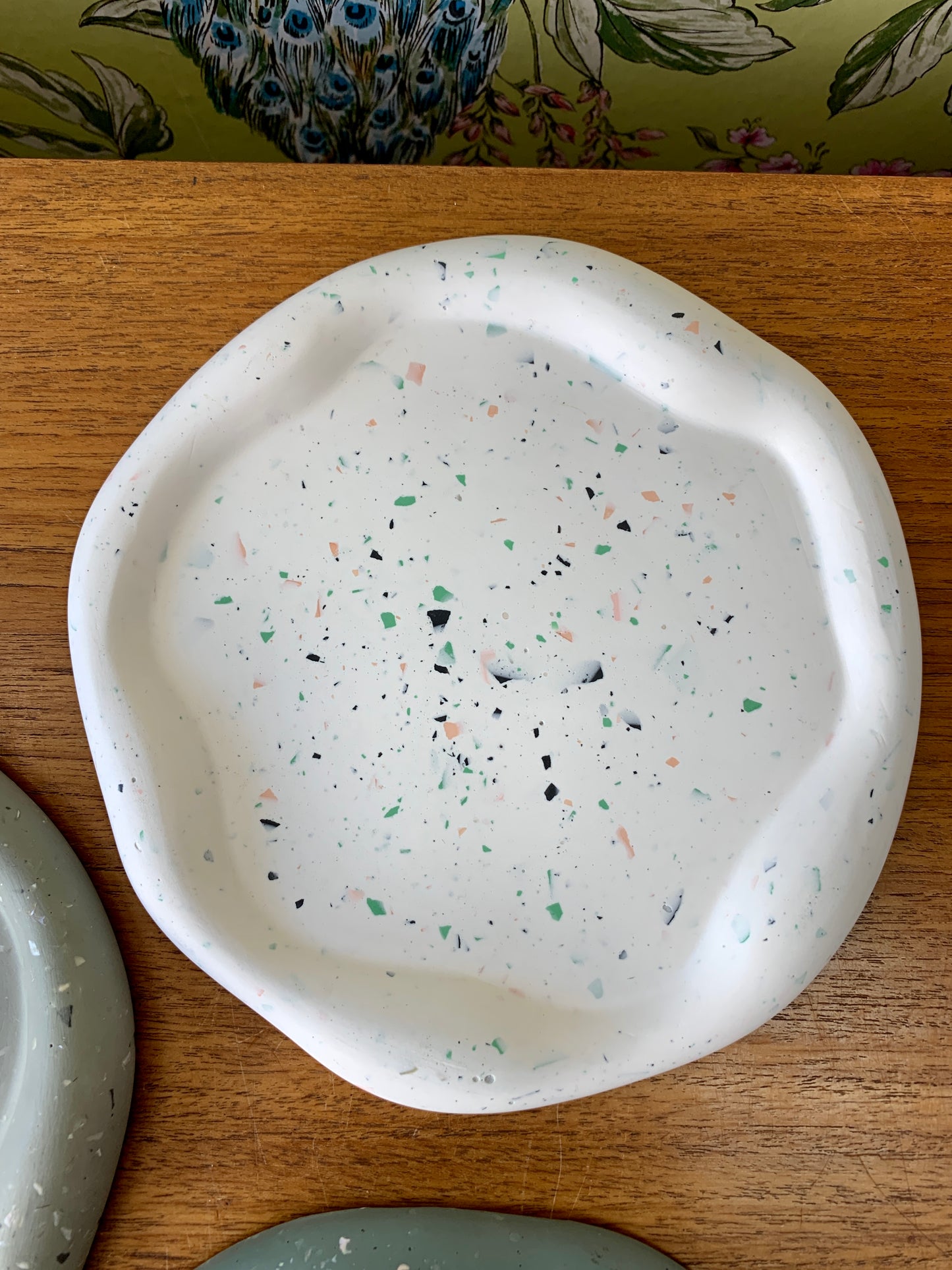 A flat wavy dish made from jesomite.  White with colourful flecks.