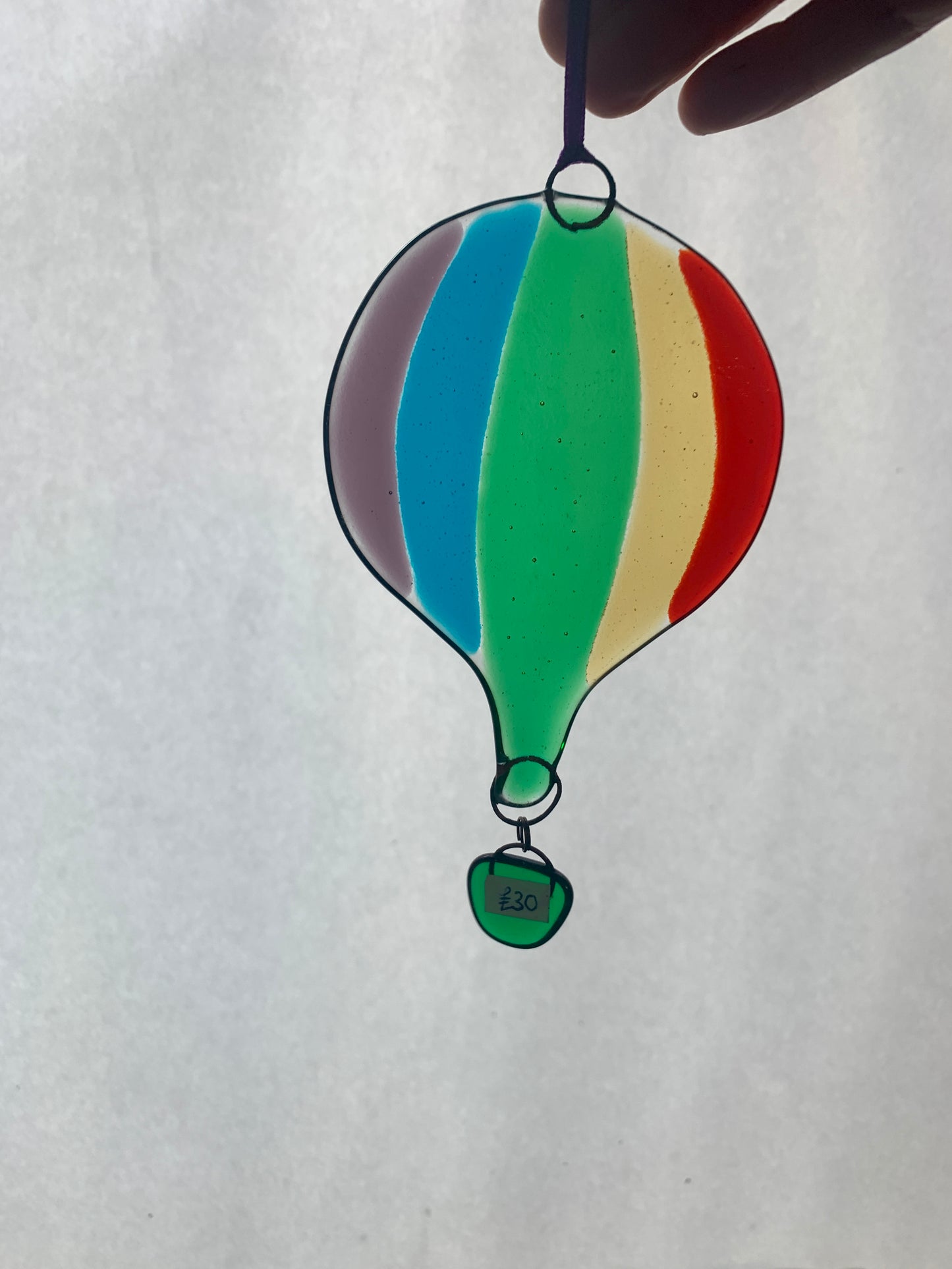 A rainbow striped fused glass hot air balloon.  A beautiful decorative glass hanging.