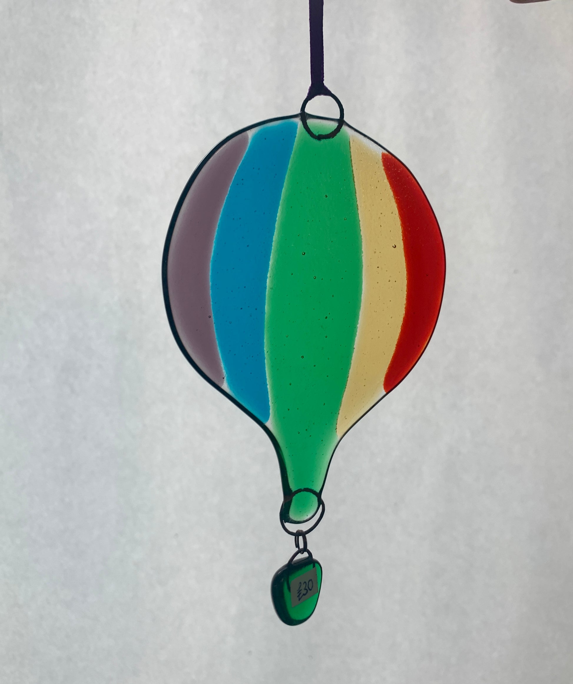 A rainbow striped fused glass hot air balloon. A beautiful decorative glass hanging.