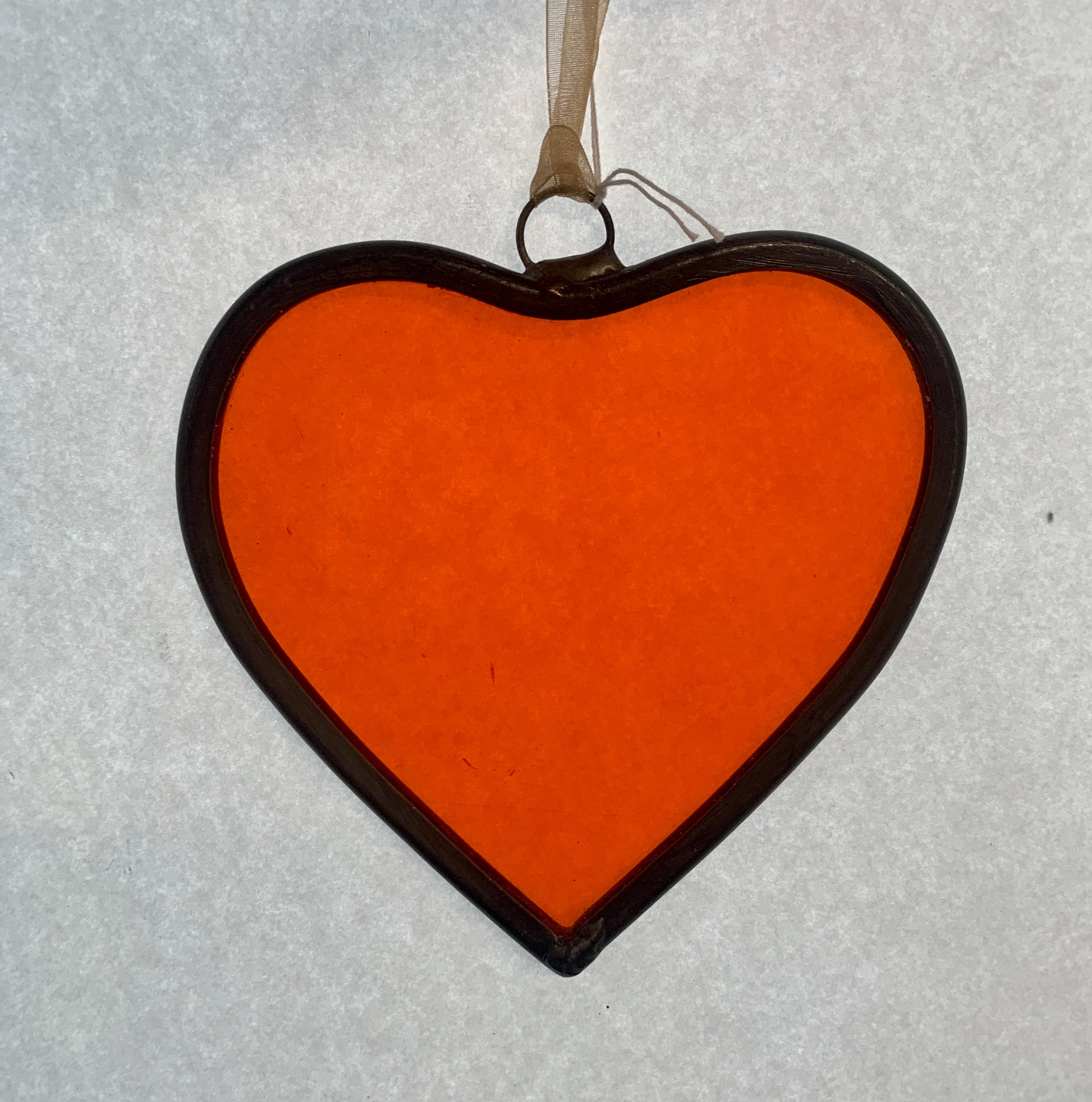 A medium sized Glass heart with a lead edging and a copper wire hook to hang in a window or outside in a tree