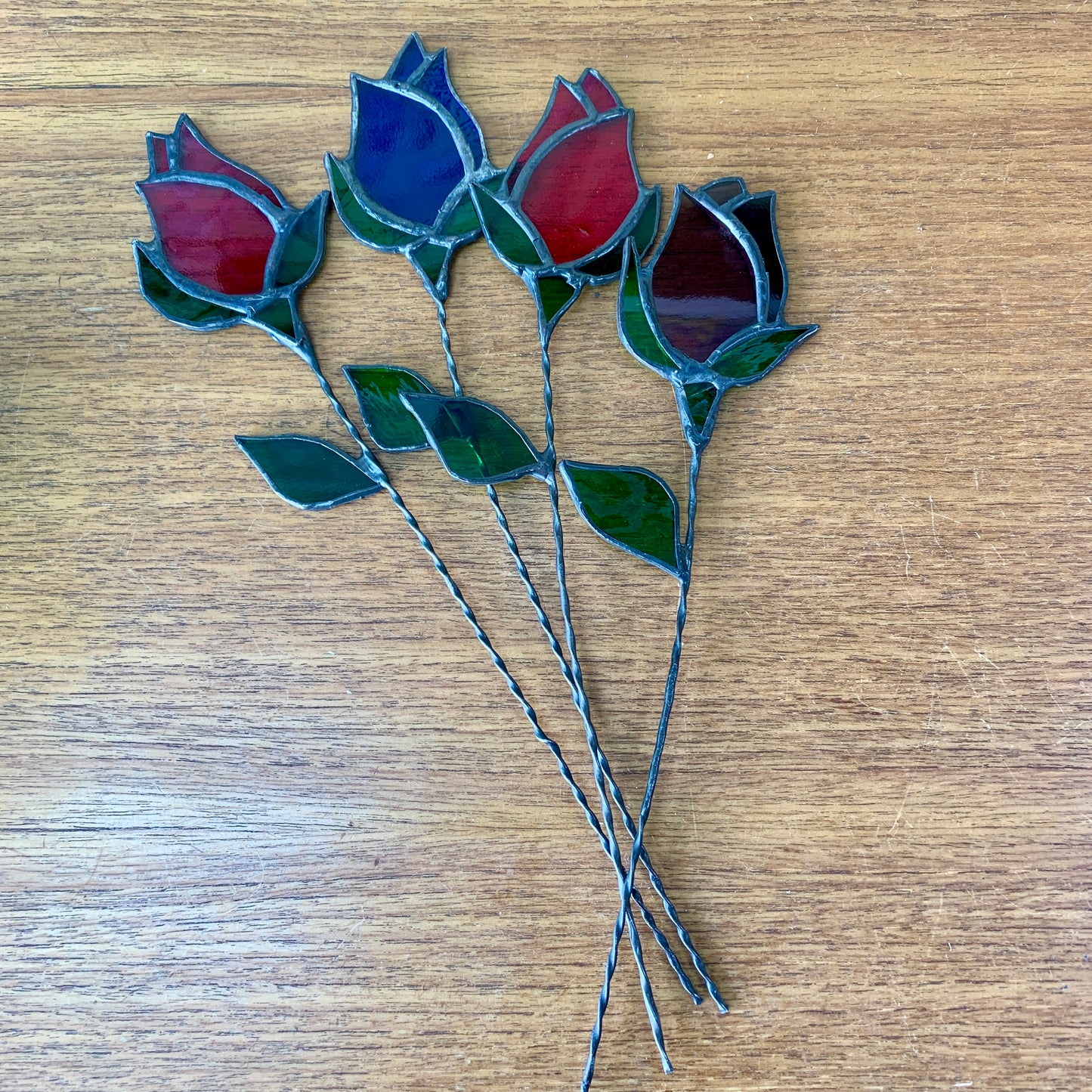 A stained glass rose bud on a copperwire stem.