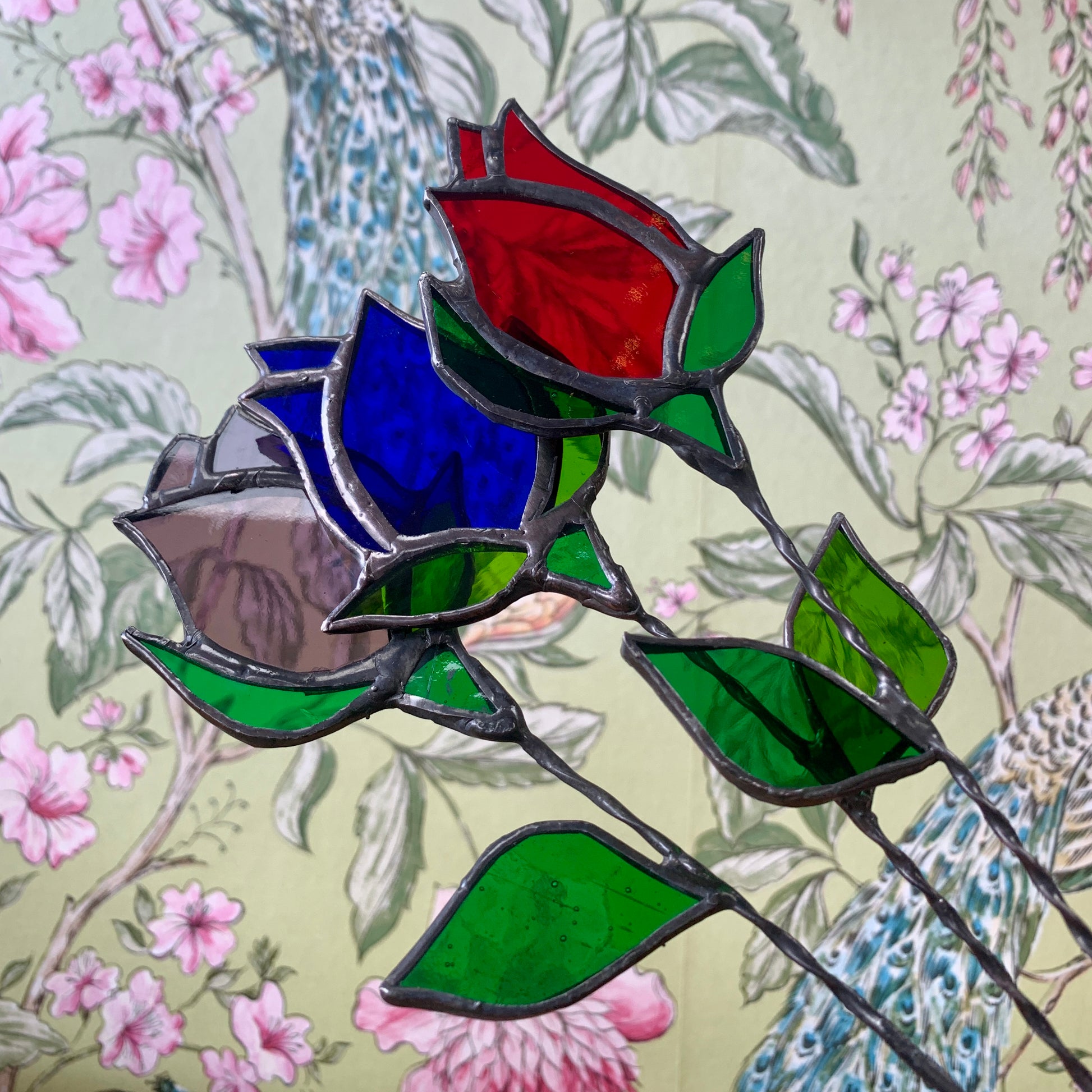 A stained glass rose bud on a copperwire stem.