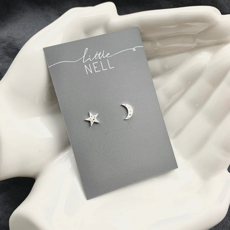 A pair of silver moon and star studs etched with tiny constellations.