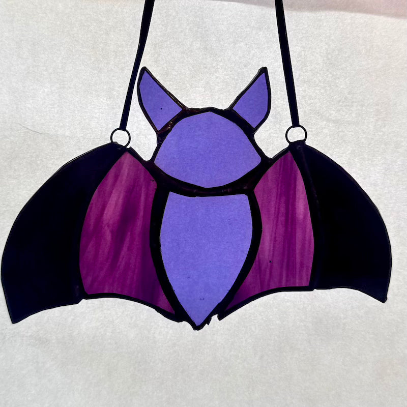 Glass Bat with black ribbon against a white background.