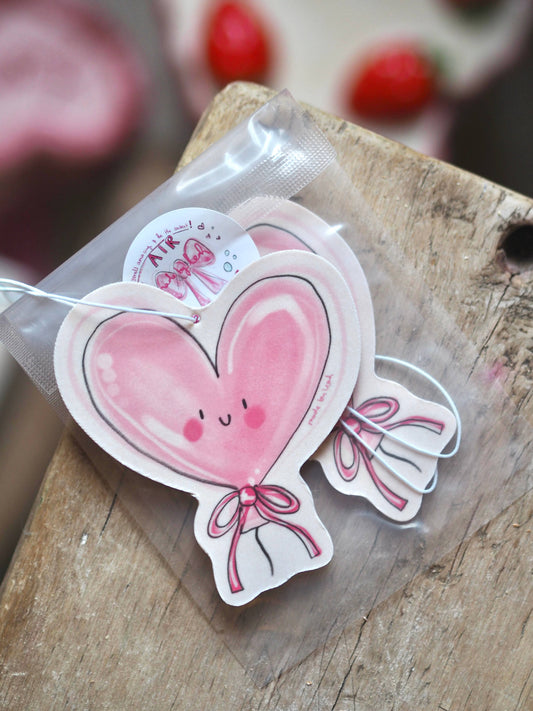 Heart-shaped balloon sticker with a smiley face on a wooden surface