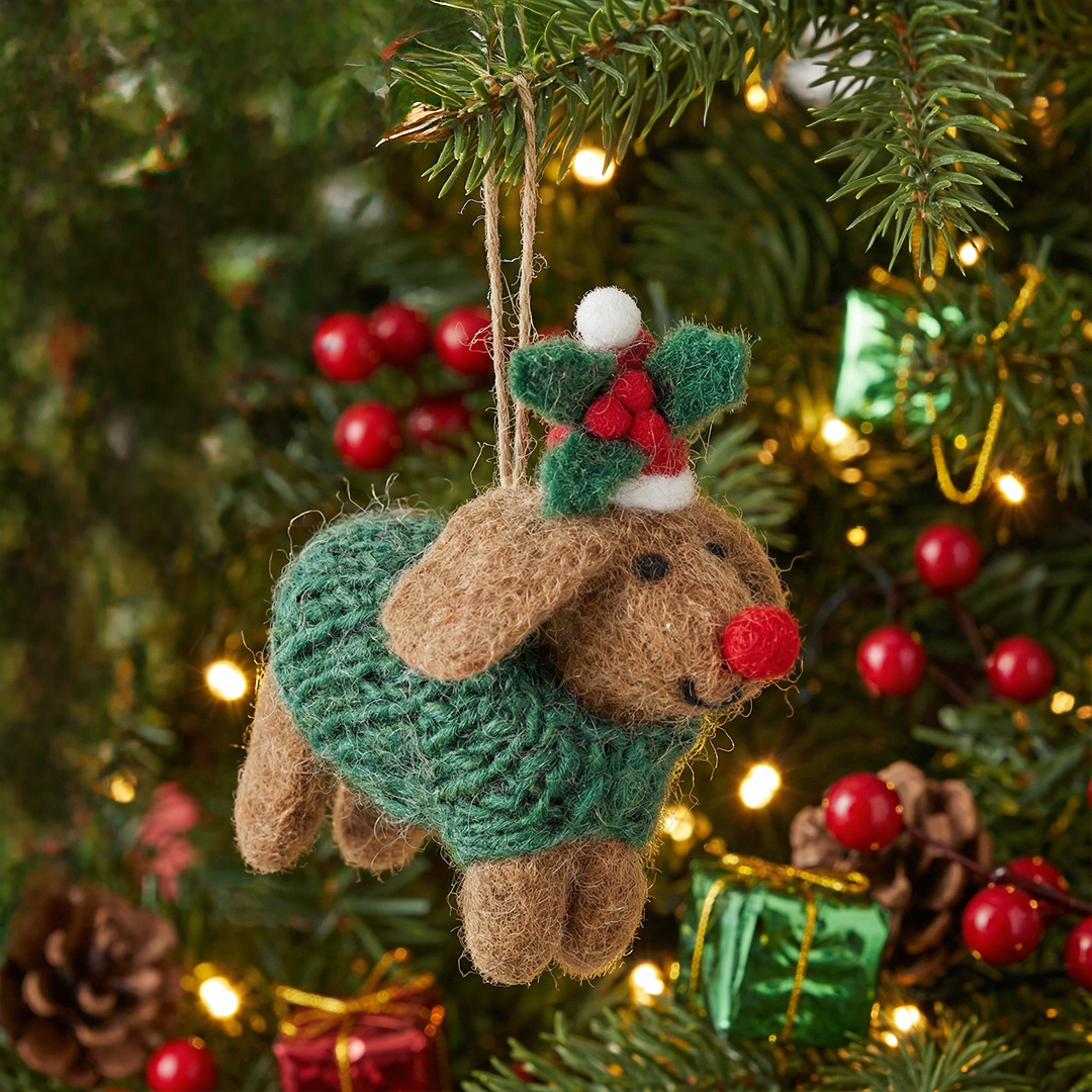 Decorative reindeer ornament in a green sweater hanging on a Christmas tree.