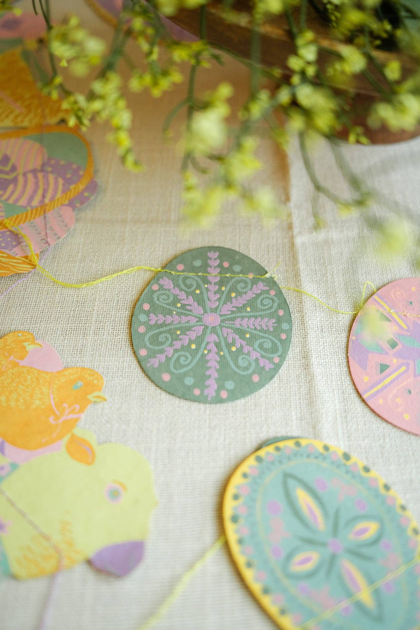 Decorative circular items with floral patterns on a textured surface with flowers in the background