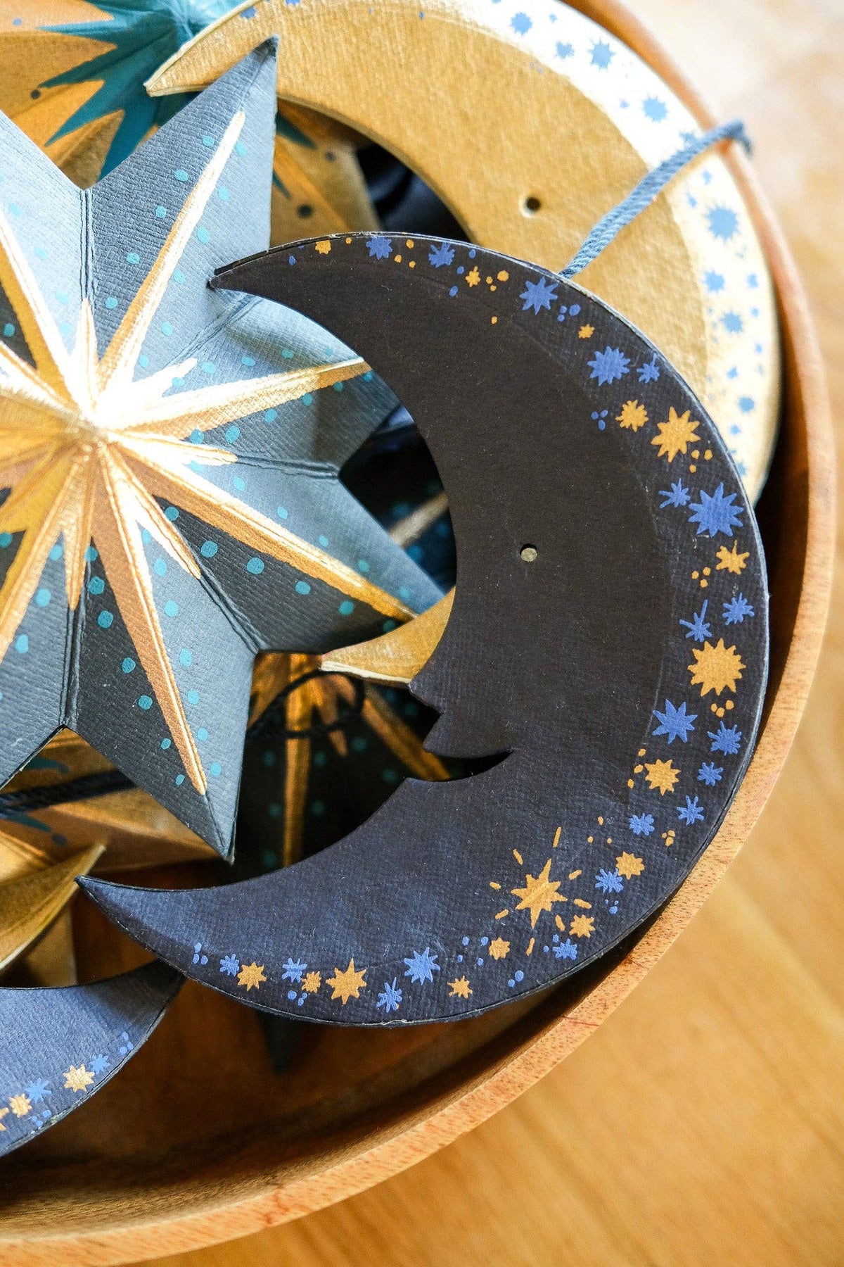 Decorative paper stars and crescent moon with star patterns on a wooden surface