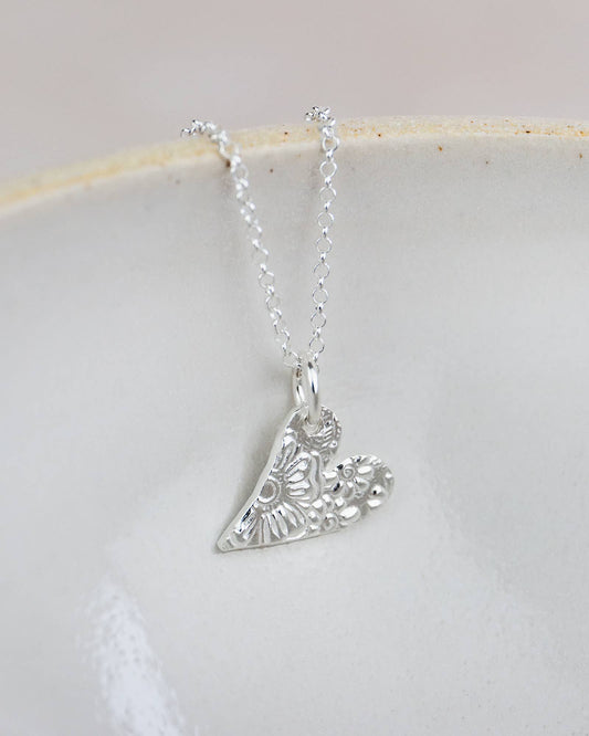 Silver necklace with a detailed pendant on a white dish
