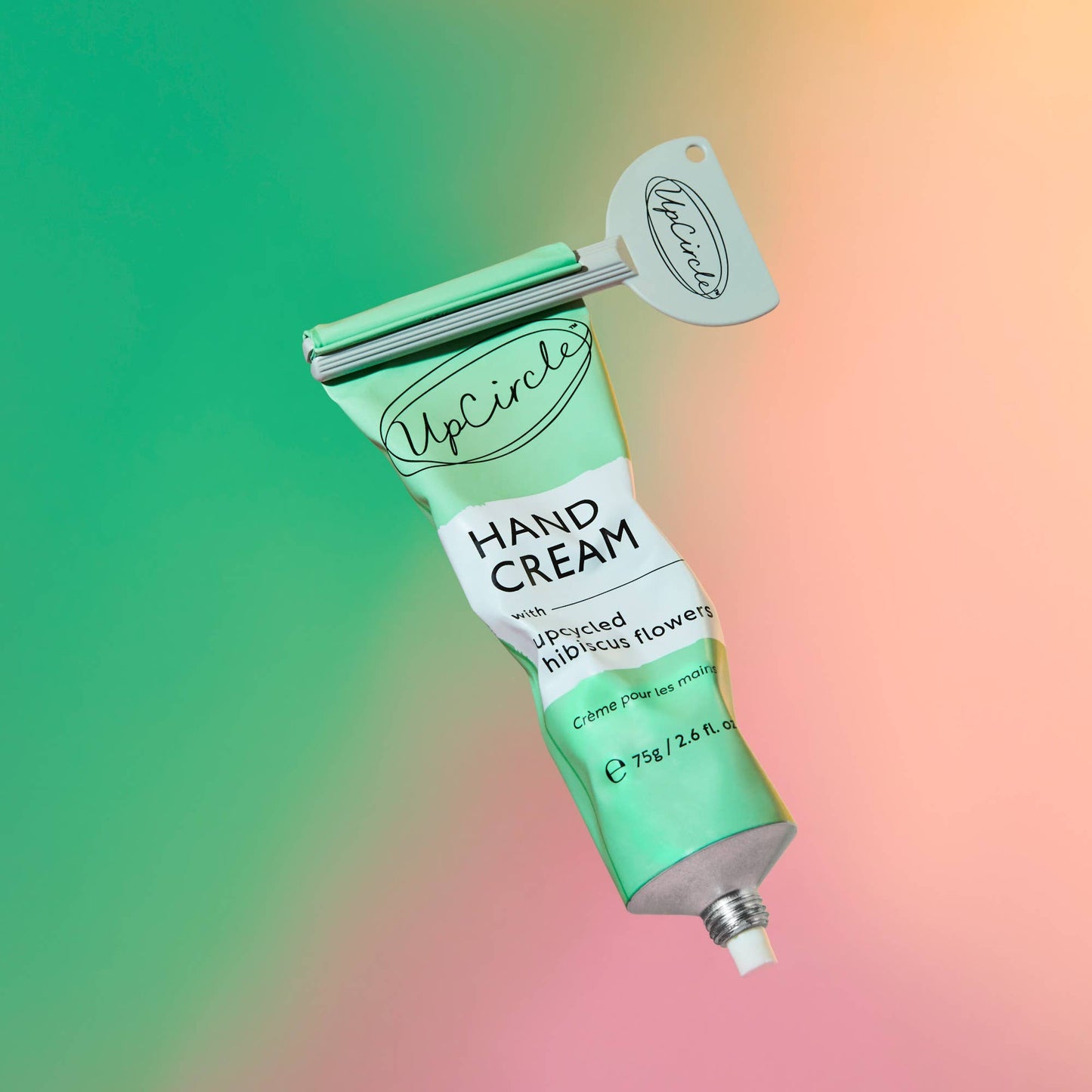 Green tube of hand cream with a silver applicator on a colorful gradient background