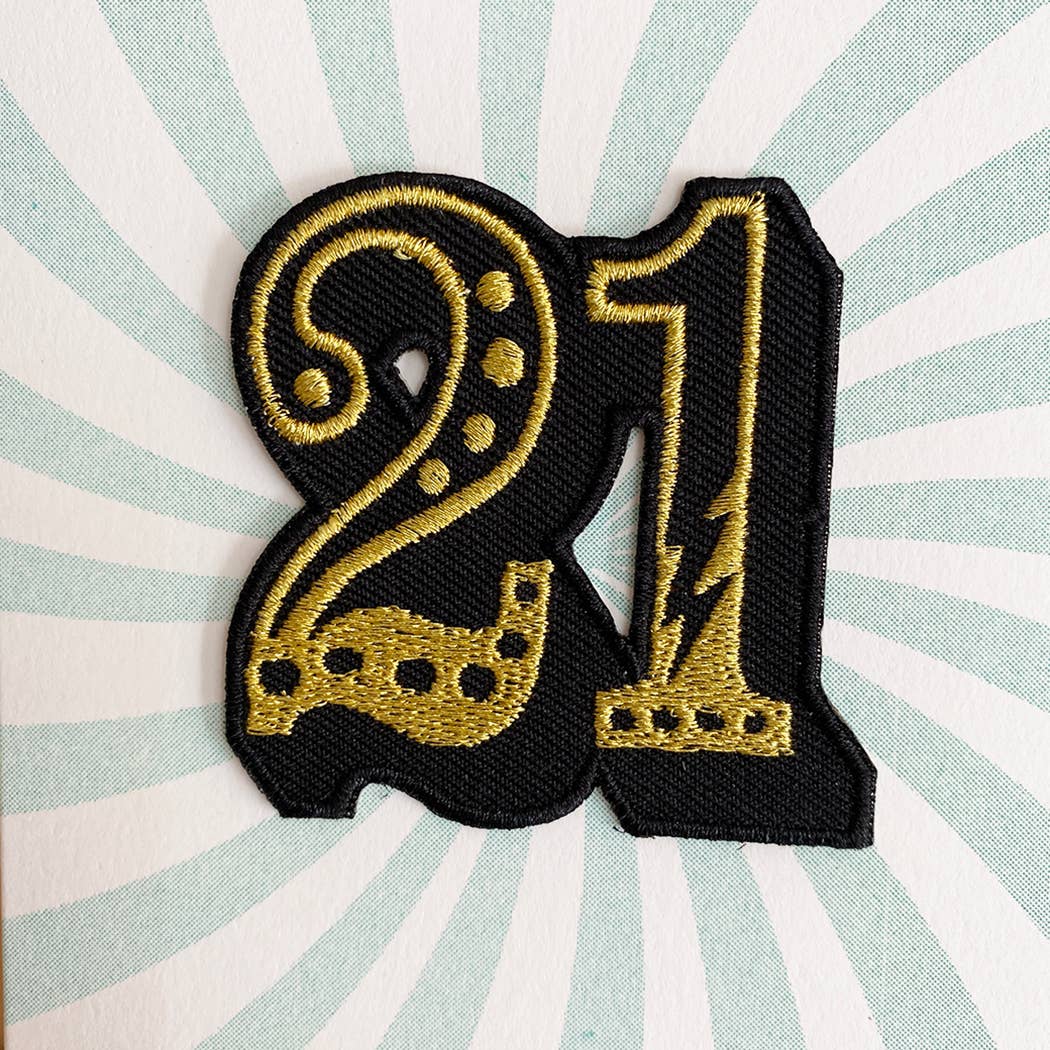 Gold embroidered number '21' patch on a striped background