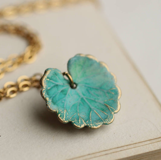 Turquoise butterfly pendant on a gold chain against a beige background