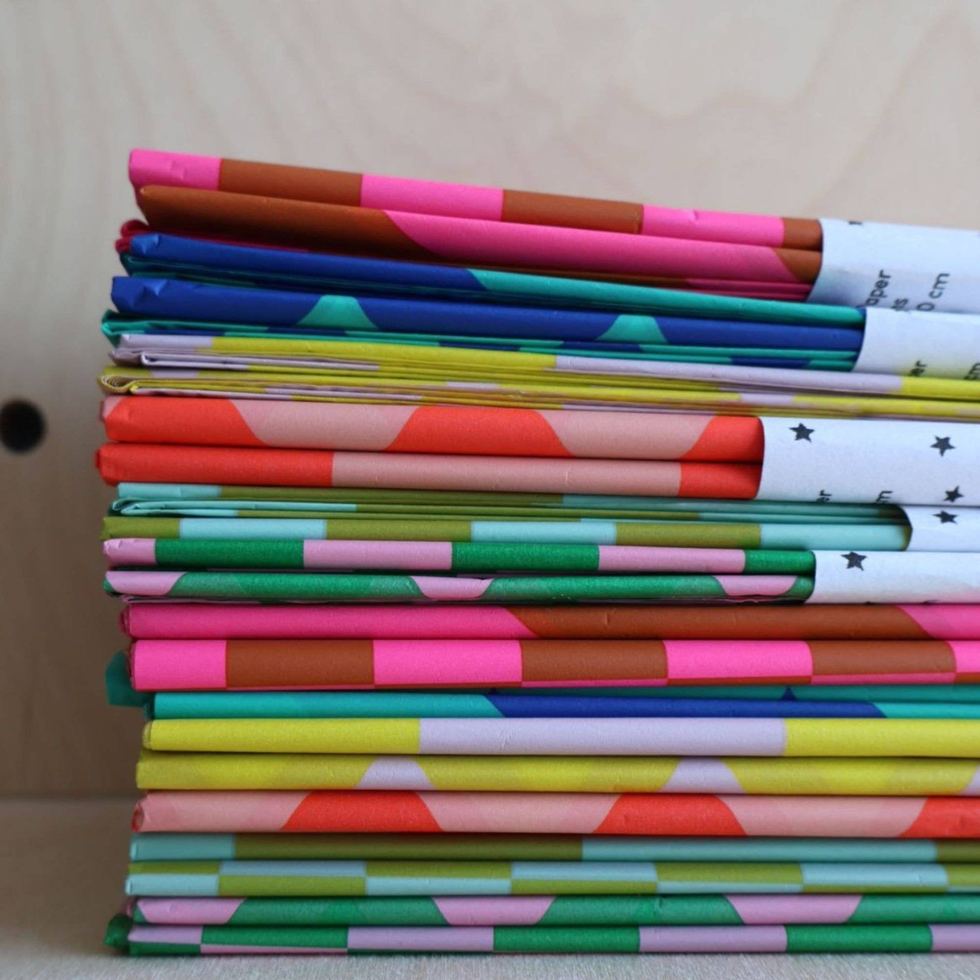 Stack of colorful notebooks with various patterns on a neutral background
