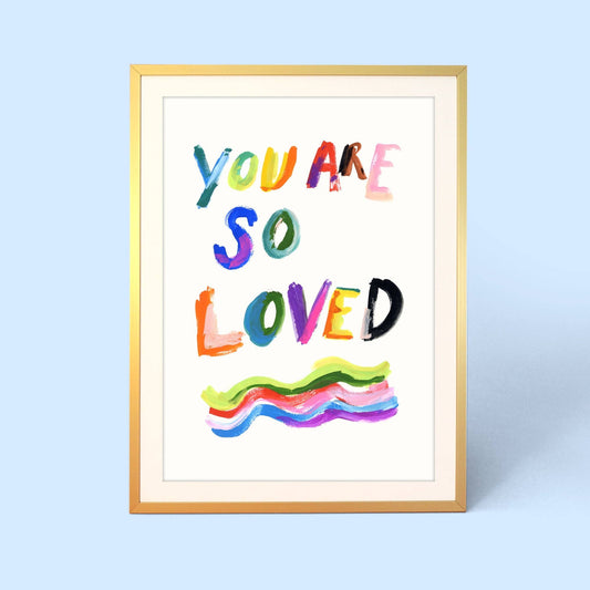 Framed artwork with colorful text 'YOU ARE SO LOVED' on a light blue background