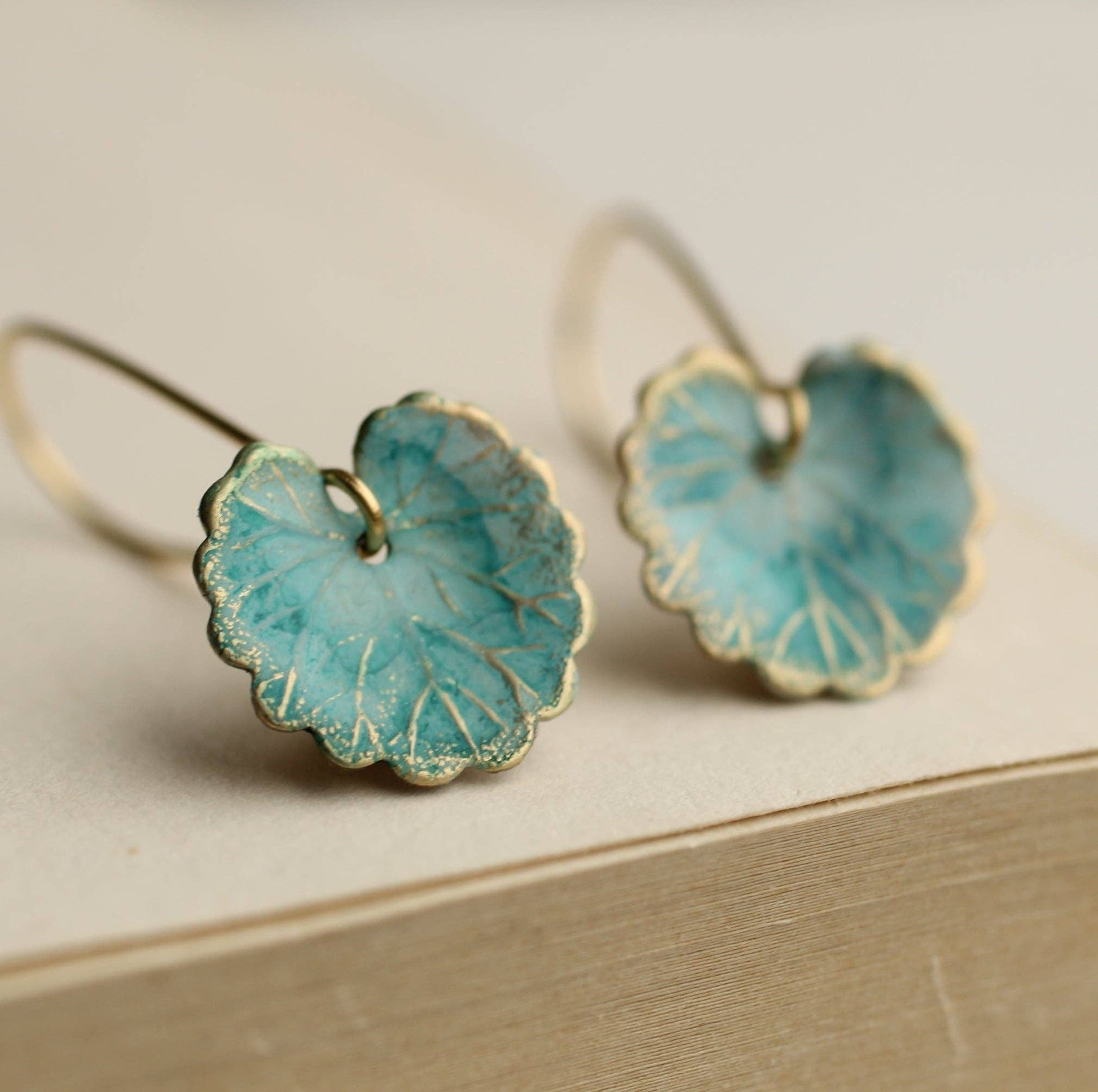 Pair of turquoise flower-shaped earrings on a beige surface