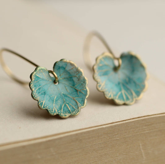 Pair of turquoise flower-shaped earrings on a beige surface