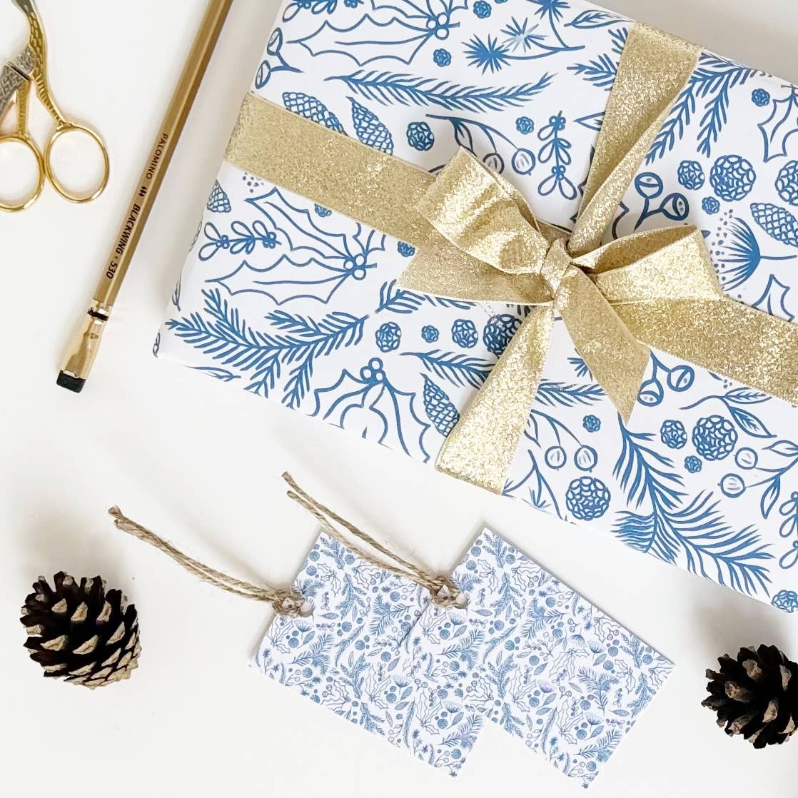 Blue on white gift wrap with festive foliage drawings.