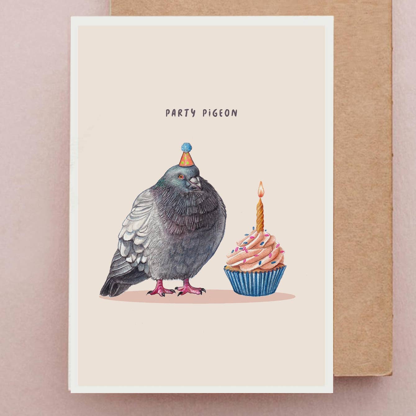 Greeting card with illustration of a pigeon wearing a party hat next to a cupcake with a candle, on a pink background.