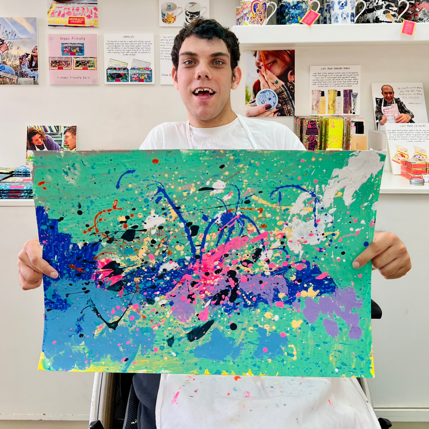 Person holding a colorful abstract painting in an indoor setting.