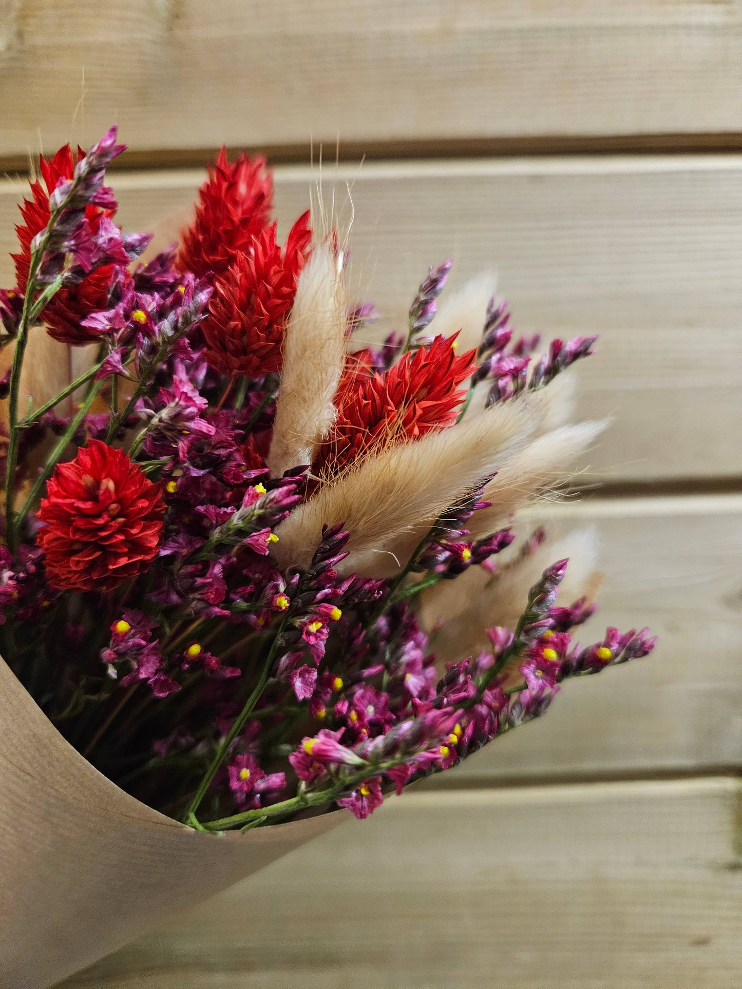 Bouquet of red and pink flowers with pampas grass on a wooden surface