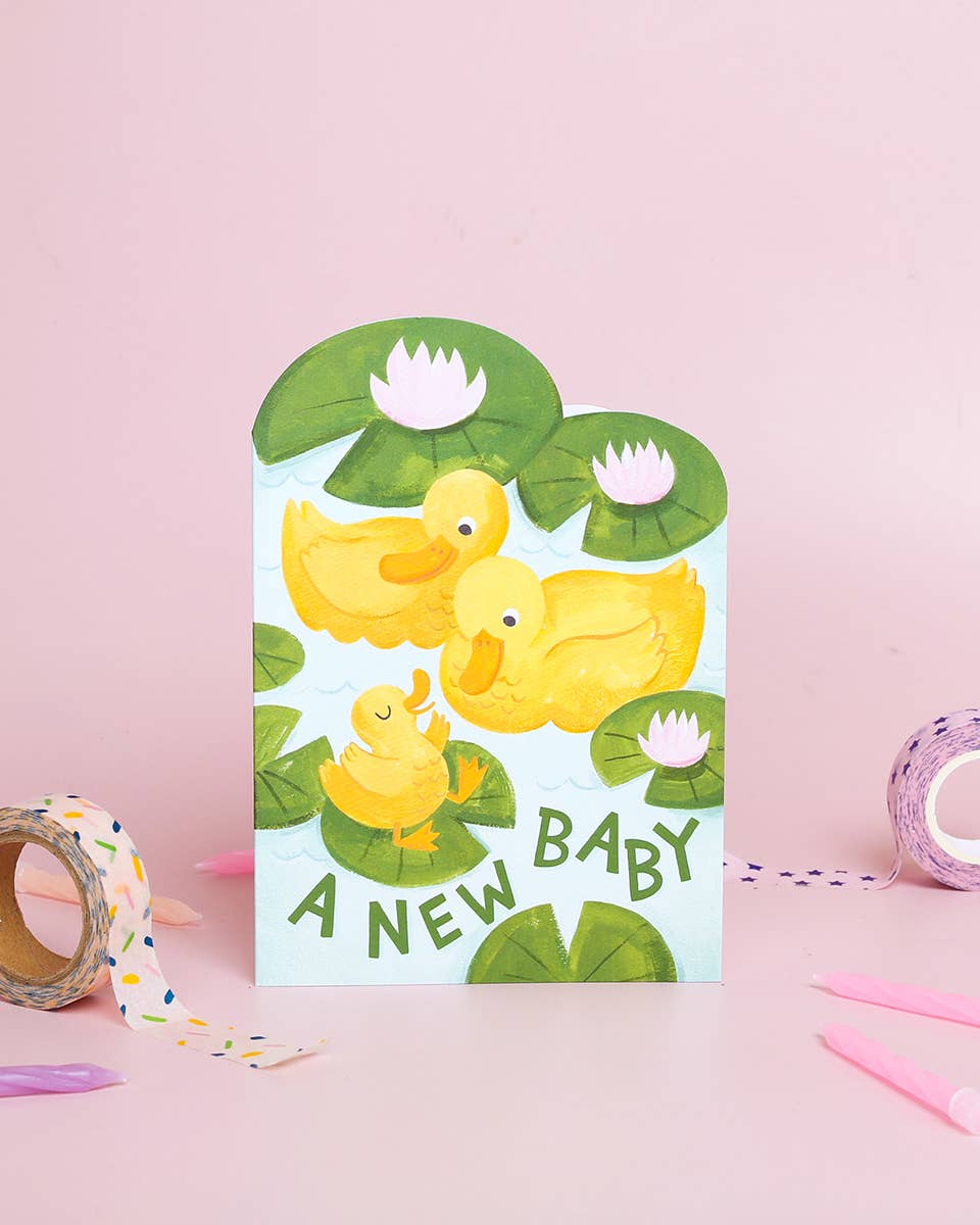 Greeting card with yellow ducks and 'A New Baby' text on a pink background