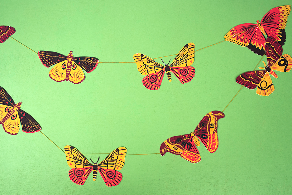 Decorative string with colorful butterfly-shaped ornaments on a green background