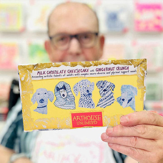 Person holding a chocolate bar with blue dog illustrations and 'Arthouse Unlimited' branding.