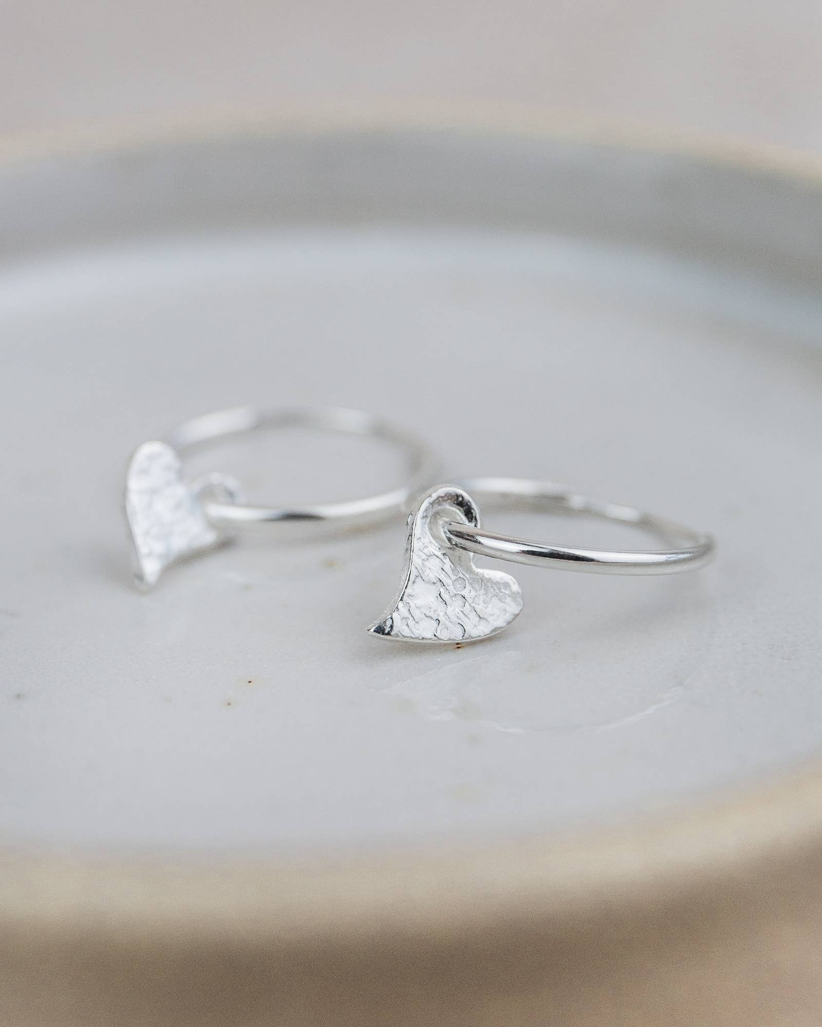 Silver heart-shaped earrings on a light gray surface