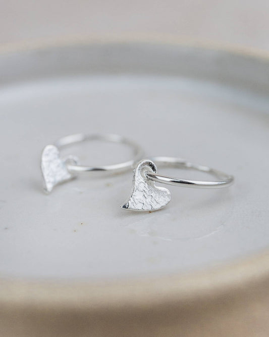 Silver heart-shaped earrings on a light gray surface