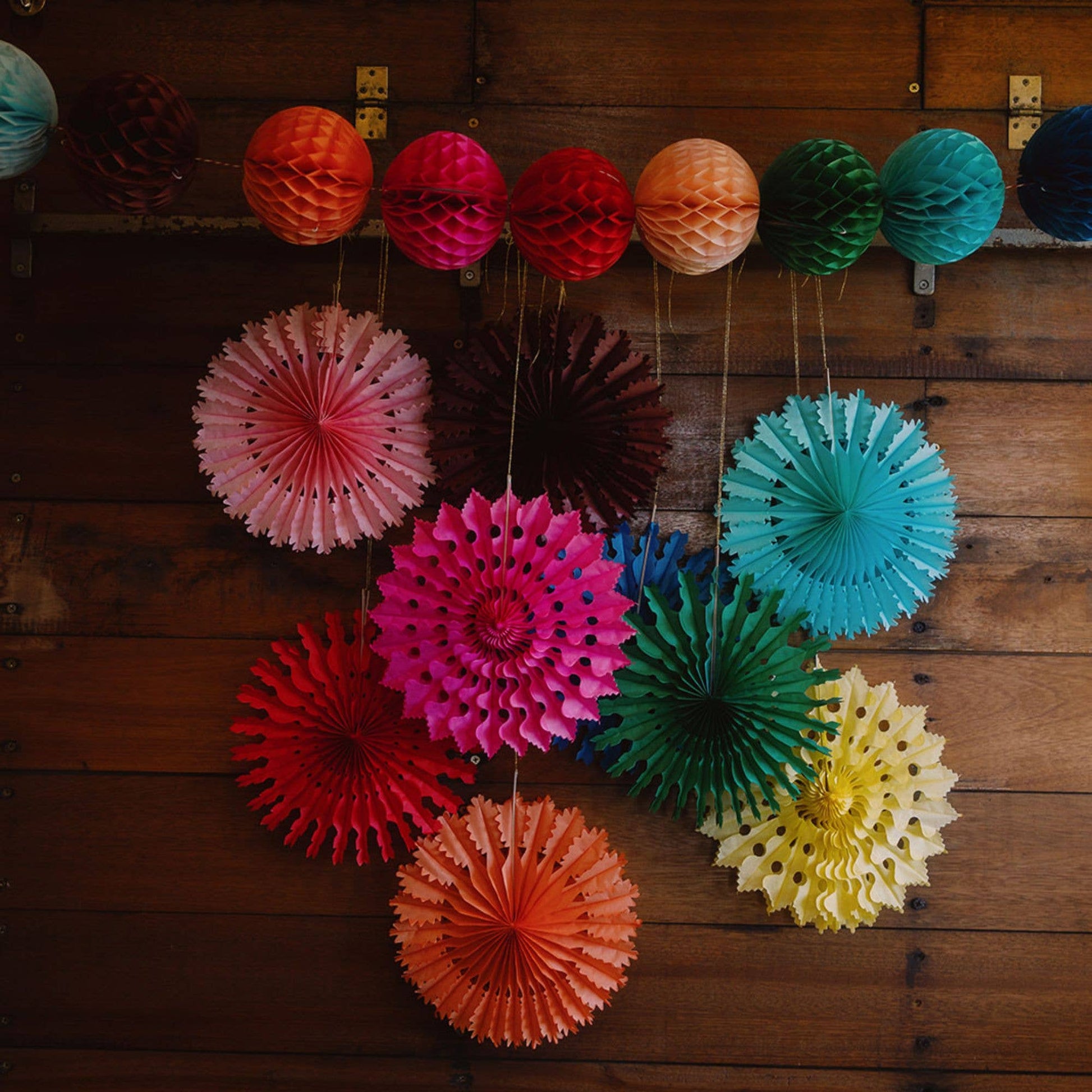 Colorful paper fans hanging on a wooden wall