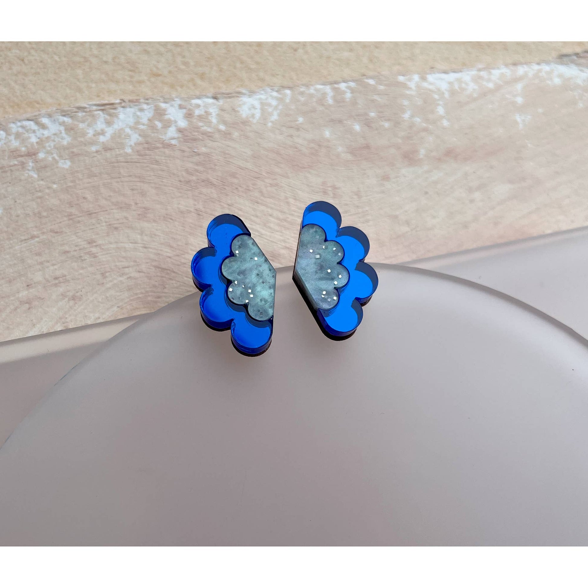 Pair of blue and green floral earrings on a light wooden surface.