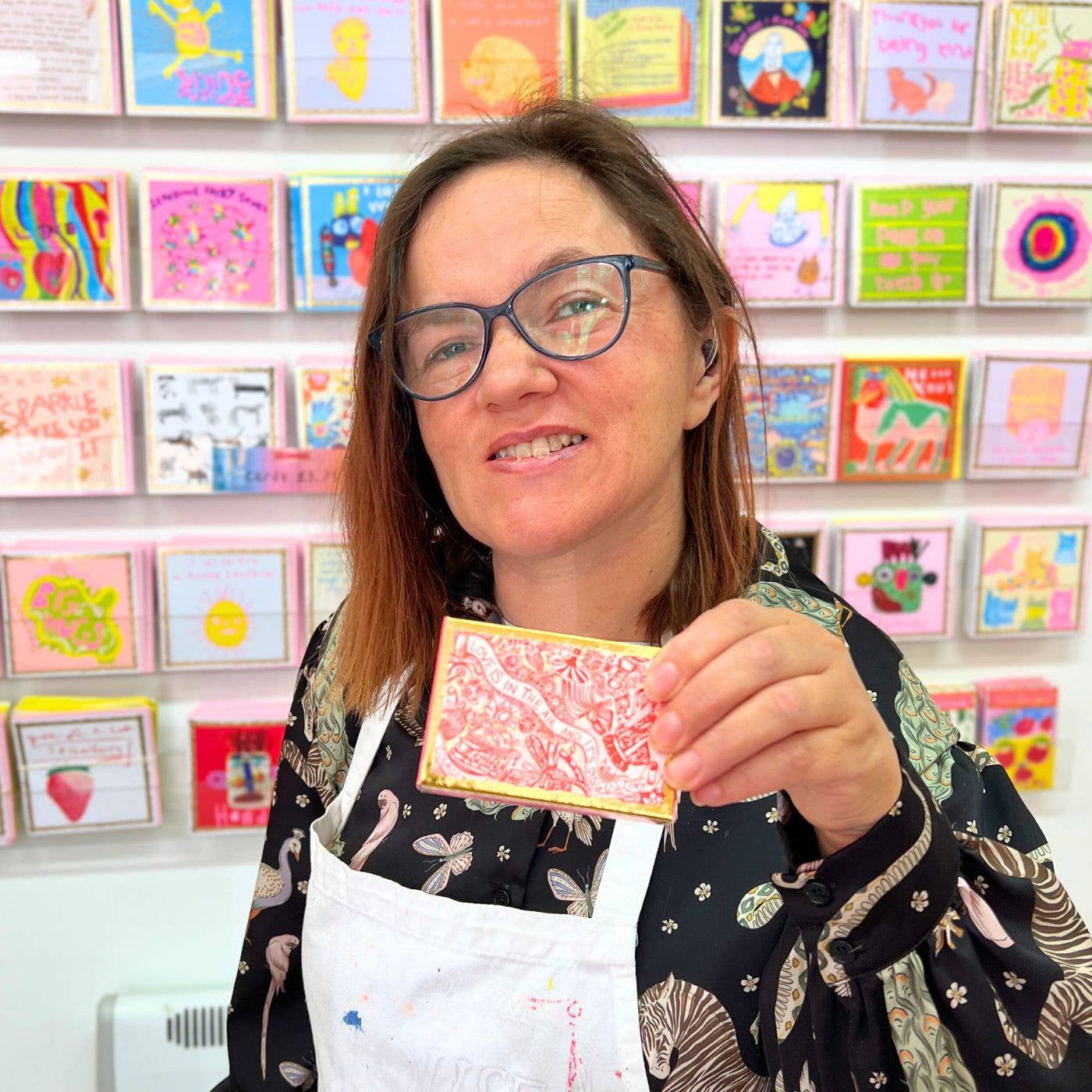 Person holding a card in front of a display of colorful greeting cards.