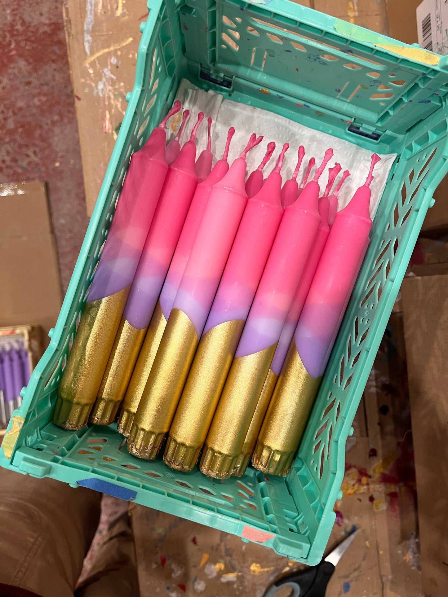 Pink and gold items in a green crate on a cluttered background