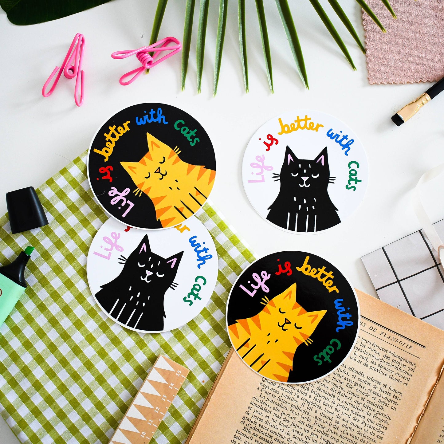 Cat-themed coasters with text on a desk with stationery items