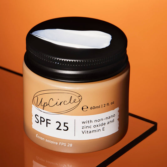 Jar of UpCircle sunscreen cream with SPF 25 on an orange background