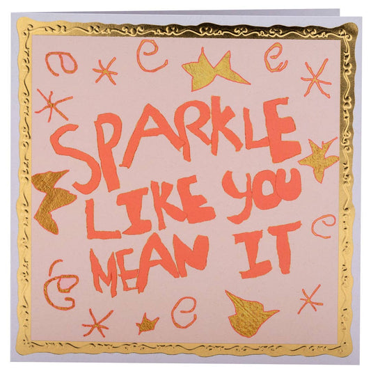 Decorative pillow with 'Sparkle like you mean it' text and star patterns on a light pink background.
