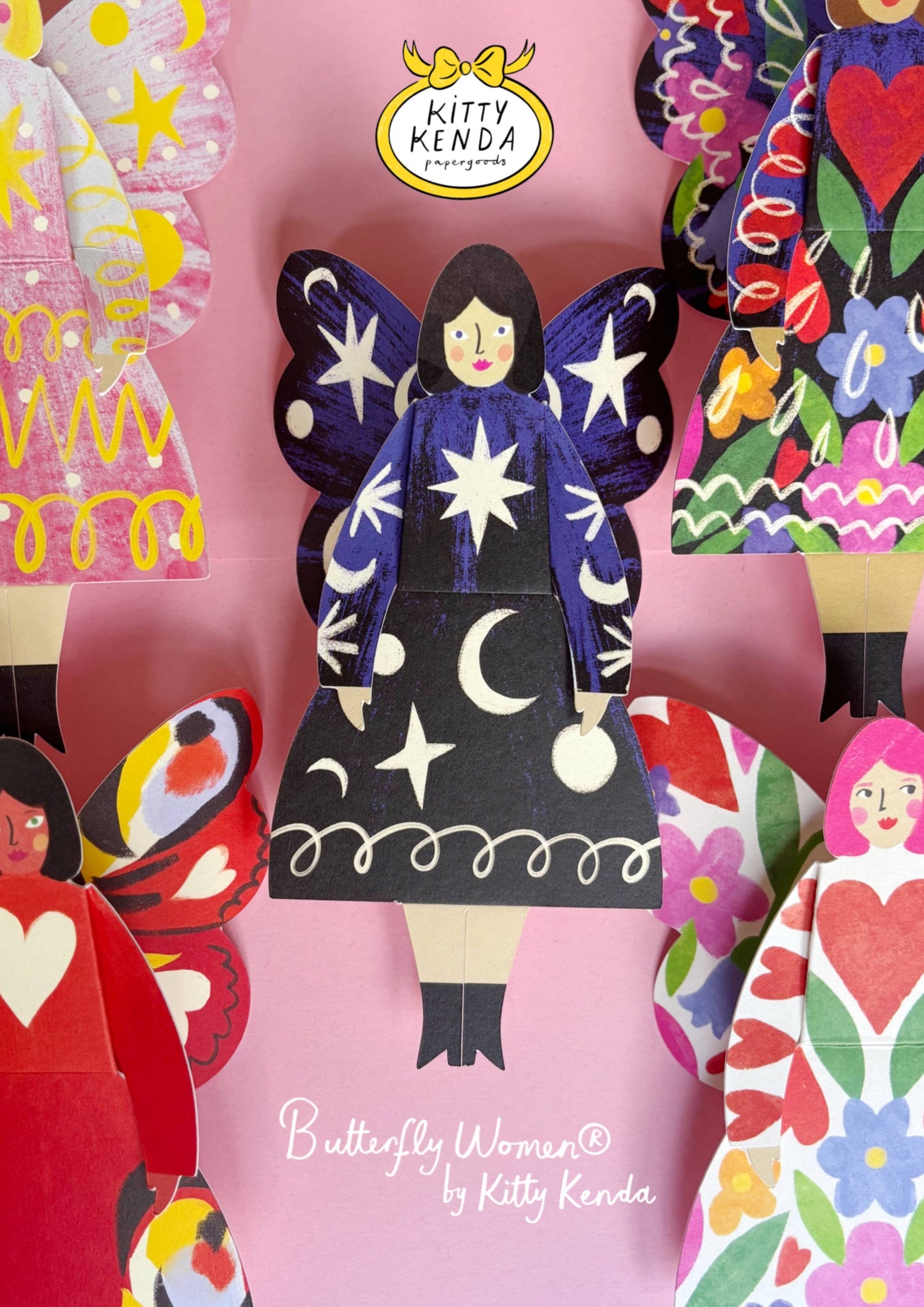 Colorful paper dolls with a prominent butterfly-themed doll on a pink background, featuring the Kitty Kenda brand.