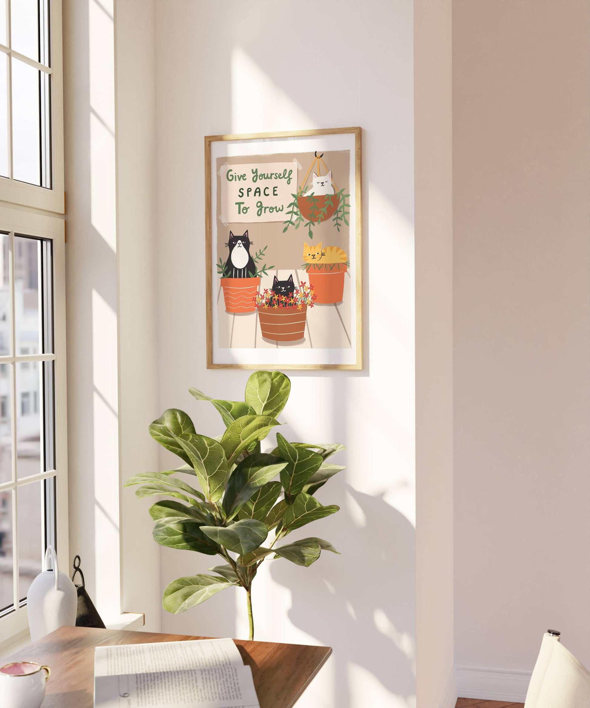 Framed artwork with cats and plants on a wall in a bright room.
