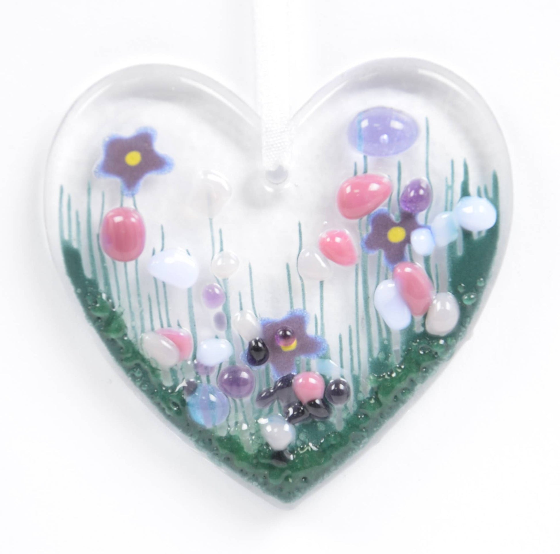 Heart-shaped glass ornament with colorful flowers on a white background