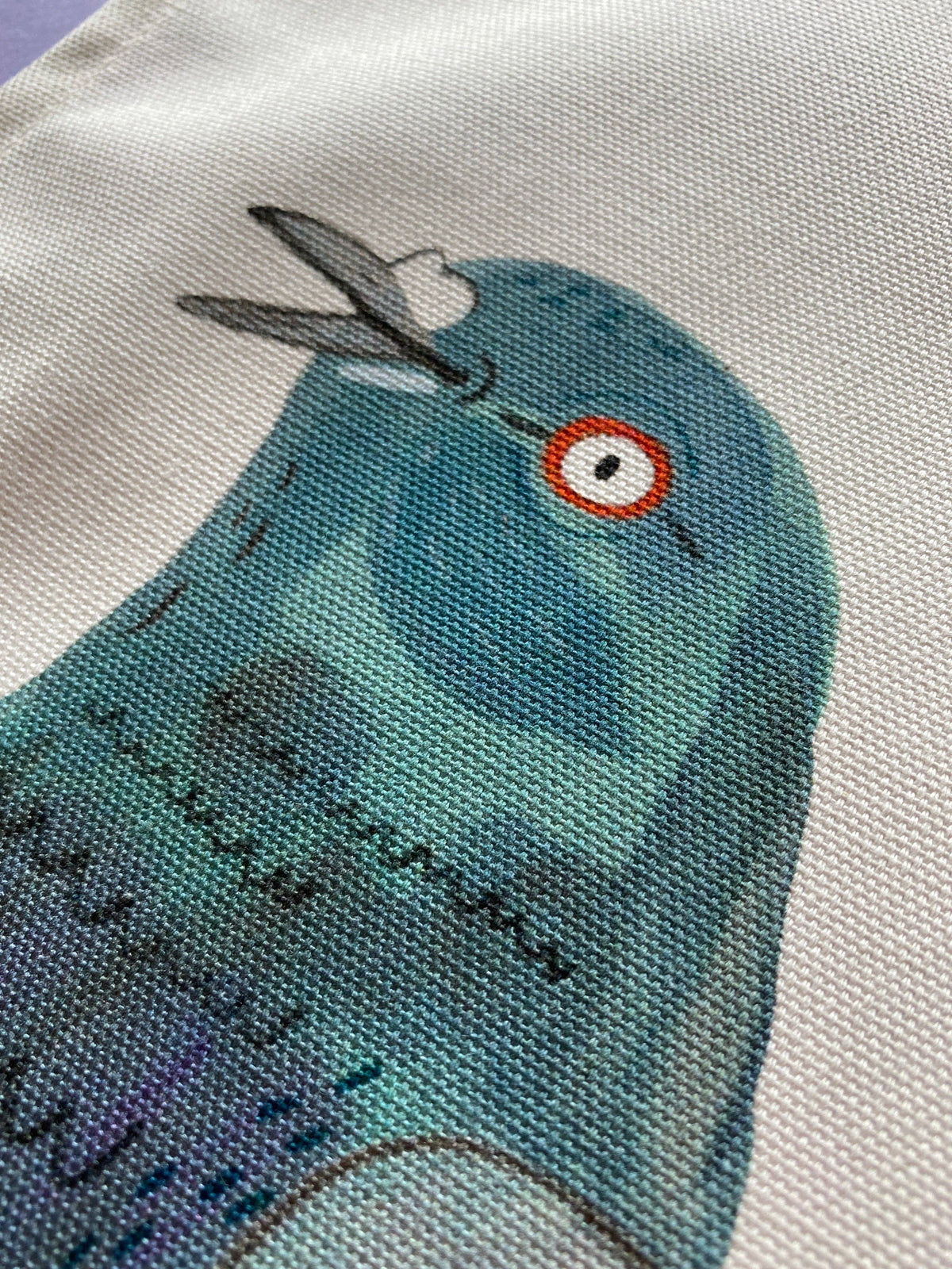 Close-up of a blue bird illustration on fabric with text.