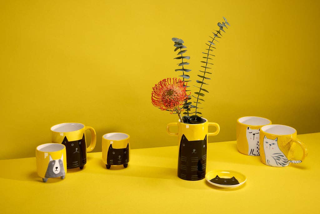 Yellow vase with handles and black cat illustration.