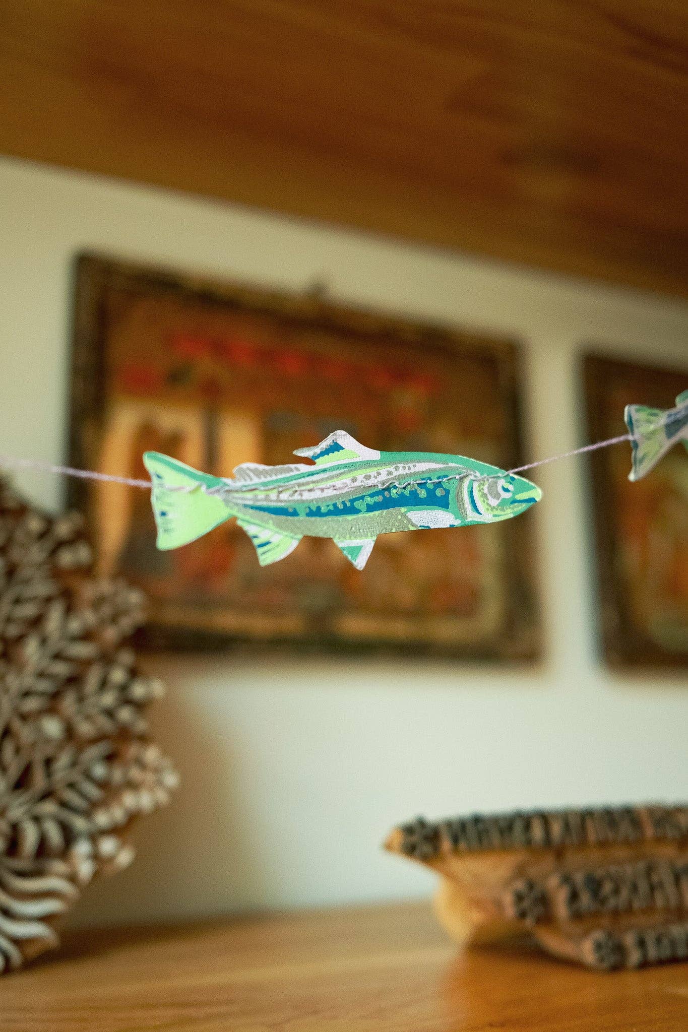 Decorative fish string art on a wooden surface with blurred background