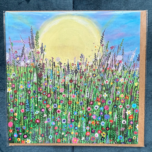 A square card featuring a hand-painted scene of wildflowers, with a large sun in the background.