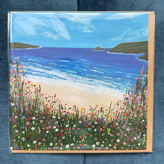 A square card featuring a hand-painted beach scene, with wildflowers in the foreground.